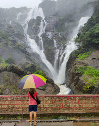 Full length of woman standing by waterfall