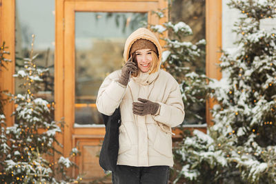 Portrait of woman standing by tree during winter