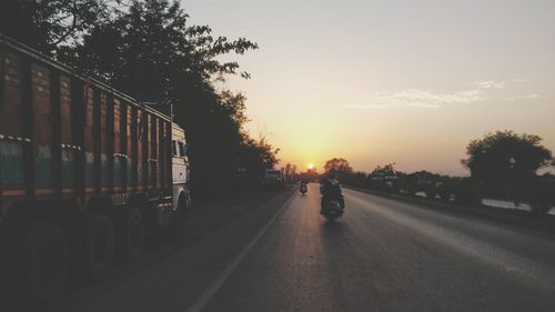 Man walking on road against sky during sunset