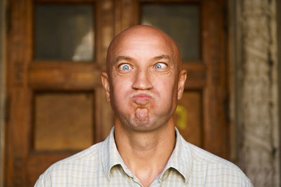 Portrait of an emotional bald guy with blue eyes. dressed in light shirt. shows