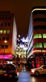 Illuminated road in city against sky at night