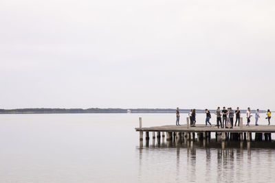 People standing by sea against clear sky