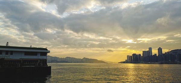 Scenic view of sea by buildings against sky during sunset
