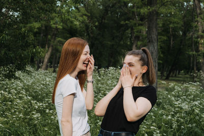 Side view of smiling young woman against trees