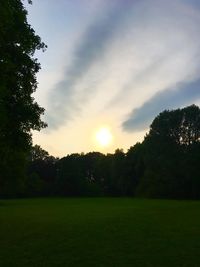 Scenic view of grassy field against sky during sunset