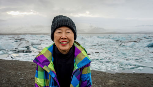 Portrait of smiling woman standing by frozen lake