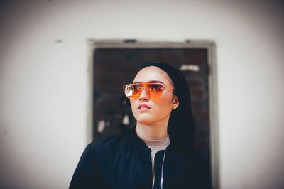 Portrait of mid adult man wearing sunglasses standing against wall