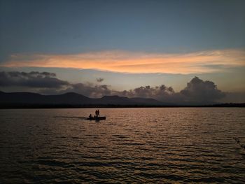 Silhouette boat in lake against sky during sunset