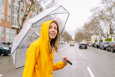 Portrait of young woman with umbrella standing in city