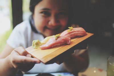 Portrait of woman carrying food on serving board