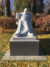 Statue of woman in park during autumn