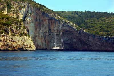 Scenic view of sea by mountain against sky