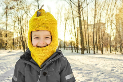 Portrait of boy wearing warm clothing standing against trees