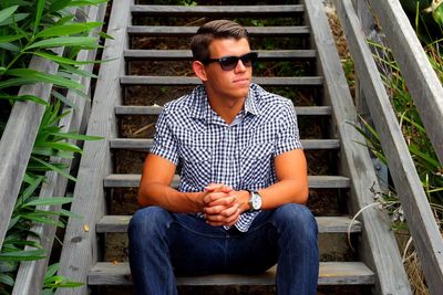 Young man sitting on staircase while looking away