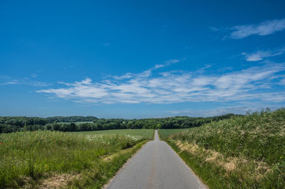 Road in agricultutal hilly landscape with crop fields