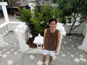 Portrait of smiling young man standing against plants