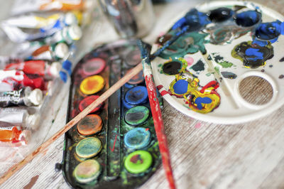 High angle view of messy palette with paintbrushes on table