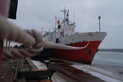 Man fishing in boat moored on sea against sky