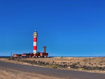 Lighthouse by sea against sky