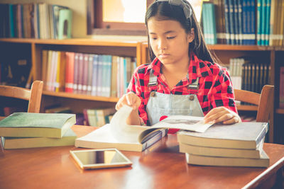 Girl reading book while sitting on table