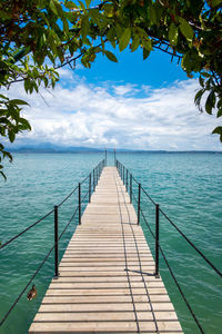 A wooden footbridge leads onto the turquoise garda lake