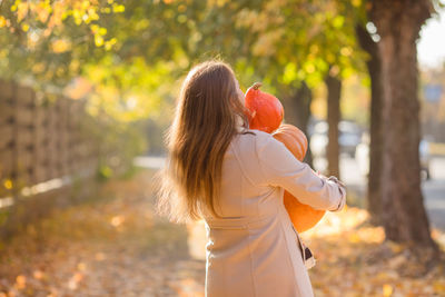 Rear view of woman with arms outstretched standing in park