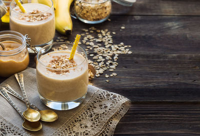 Fresh homemade smoothie with banana, oat flakes and peanut butter on rustic wooden background 