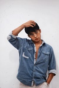 Young man standing against white wall