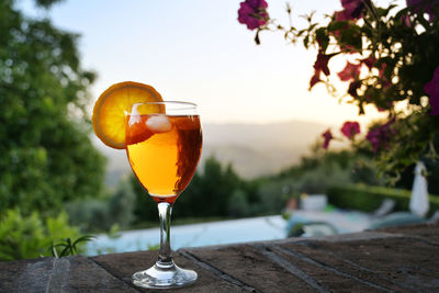 Close-up of wineglass on table against orange sky