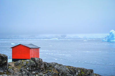 Red building by sea against sky