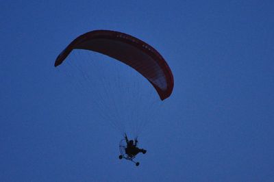 Low angle view of paragliding against clear blue sky