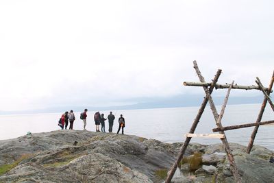 People standing on rock by sea against sky