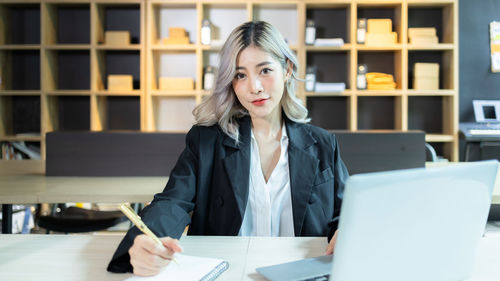 Portrait of young businesswoman using laptop while sitting at table