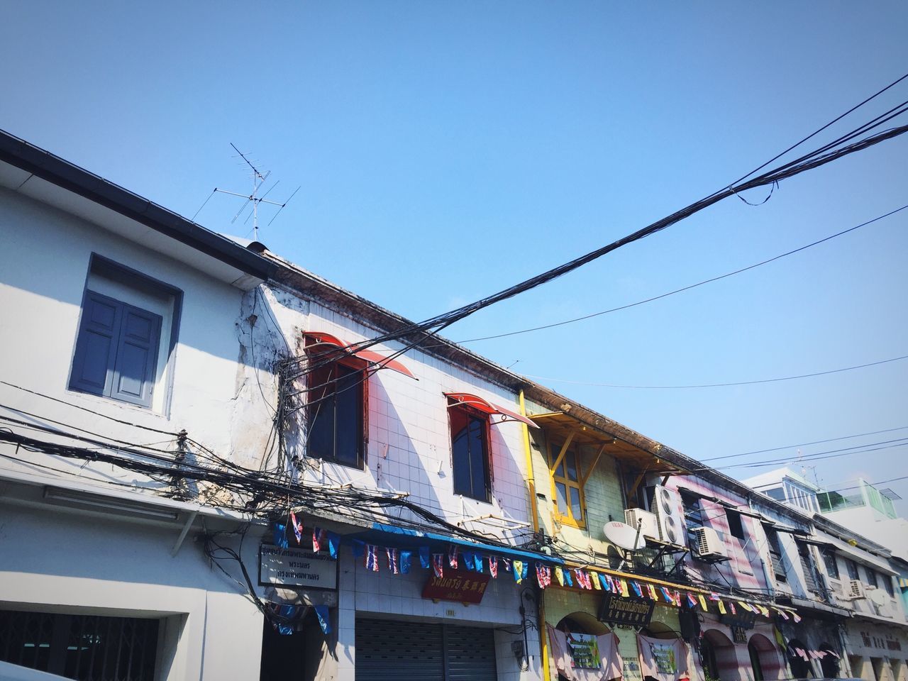 building exterior, architecture, built structure, low angle view, clear sky, residential building, residential structure, cable, building, blue, house, power line, window, city, day, outdoors, roof, balcony, hanging, sky