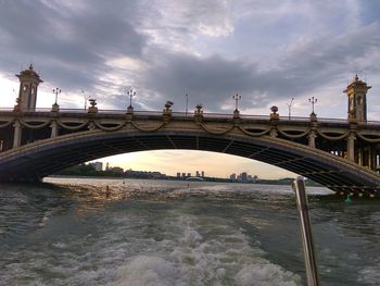 Bridge over river against cloudy sky