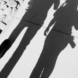 Low section of people standing on shadow