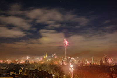 Firework display over city buildings against sky at night