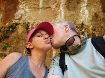 Portrait of couple kissing against wall