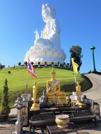 Statue by temple against clear sky