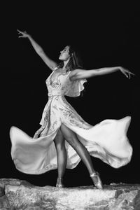 Midsection of woman dancing against black background