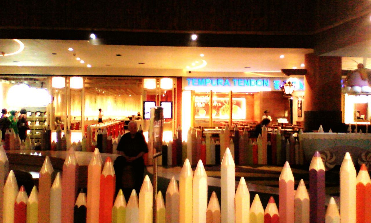 indoors, illuminated, restaurant, lighting equipment, architecture, built structure, ceiling, night, table, incidental people, store, retail, chair, men, window, architectural column, in a row, hanging, reflection