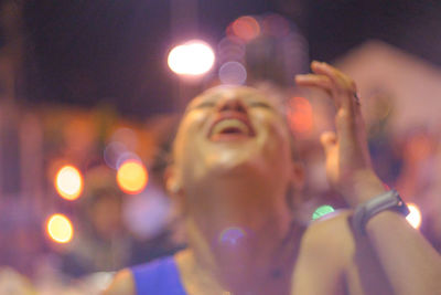 Defocused image of happy woman laughing at night