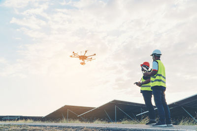 Low angle view of men working against sky