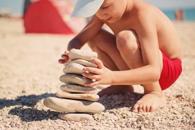 Midsection of boy sitting on sand at beach