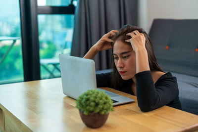 Woman looking at camera while sitting on table