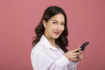 Young woman using mobile phone against yellow background