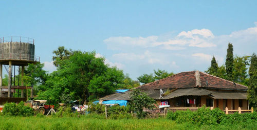 Houses and trees on field against sky