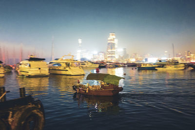 Boats moored in river against sky in city