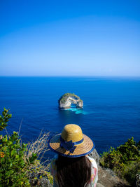 Rear view of woman looking at sea against blue sky