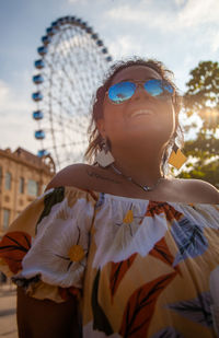 Midsection of woman wearing sunglasses standing against sky